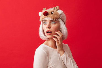 Excited young shocked woman dressed in carnival christmas costume posing isolated over red wall background.