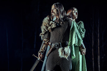 Medieval knight with his beloved lady. Dark forest on the background. © diter