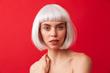 Amazing young shocked woman dressed in carnival wig posing isolated over red wall background.