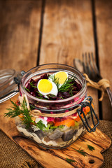 Traditional Russian layered betroot and herring salad (under a fur coat) in glass jar