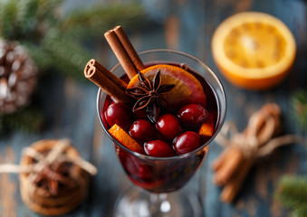 Christmas hot mulled wine in a glass with spices, citrus fruit and cranberry. Christmas atmosphere. 