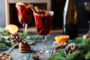 Christmas hot mulled wine in a glass with spices, citrus fruit and cranberry. Christmas atmosphere. 