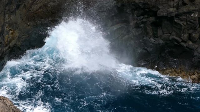 Big waves crashing on a cliff of rocks dark of lava on the coast of the island of "La Palma", Canary Islands, Spain.