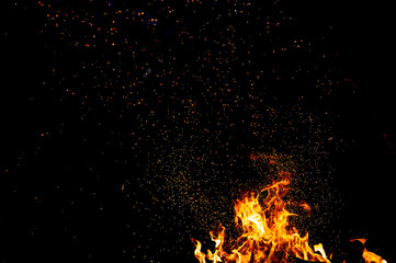 Fototapeta na wymiar Burning woods with firesparks, flame and smoke. Strange weird odd elemental fiery figures on black background. Coal and ash. Abstract shapes at night. Bonfire outdoor on nature. Strenght of element.