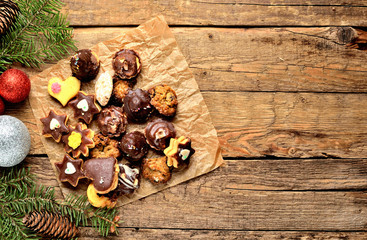 Top view of christmas sweets with different types of candy on baking paper and Christmas decorations in background