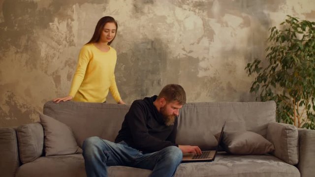 Surprised woman caught her ashamed boyfriend viewing some embarrassing content online on laptop in domestic room. Angry pretty girl caught confused bearded man texting with mistress using laptop.
