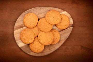Gingernsaps on a wooden tray, shot from the top on a dark rustic background with a place for text