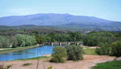 Fototapeta na wymiar Tuscany, landscape of countryside near Arezzo with the Arno river and the Ponte a Buriano bridge in the distance