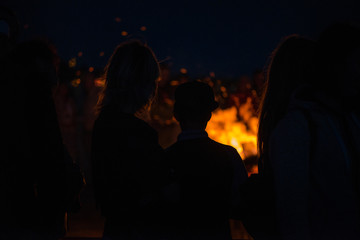 Large burning bonfire with soft glowing flame and sparkles flying all around. Romantic summer evening, people relaxing and enjoying calmness at the seaside during the Night of ancient lights