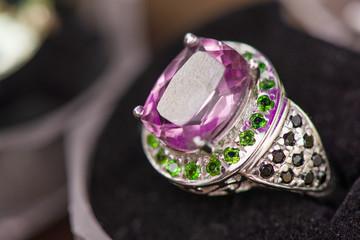 Macro shot of silver engagement ring in gift box on colorful, sparkling background. Ring made of sapphire, amethyst, chrome diopside stones. Healing, natural crystals and , powerful energy