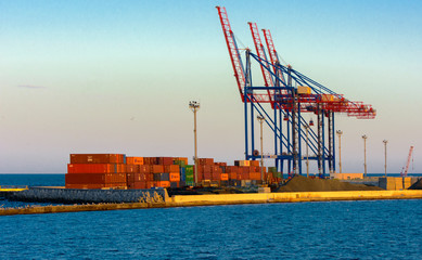 Fototapeta premium Odessa, Ukraine - August 8, 2018. Big working cranes for loading containerships and various cargoes to the ships at the shipyard against a beautiful evening blue sky in soft colors. Cargo delivery