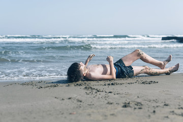 Fototapeta na wymiar Happy teen boy having fun in the healing mud from the sea on the beach