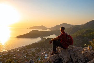 Traveler relaxes on a cliff and admires the amazing sea bay