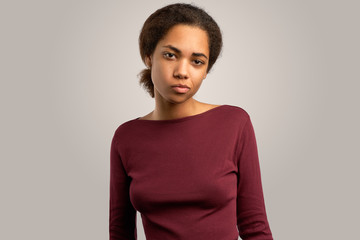 a young black woman with a dissatisfied face with a chicken looks at the camera. Isolated Studio portrait on white background