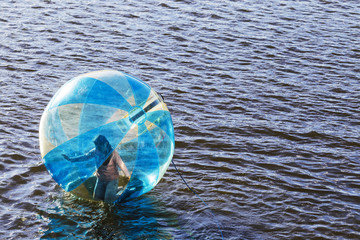 Water ball (similar to zorb or Human Hamster Ball) with person inside on river surface. Vltava river in Prague