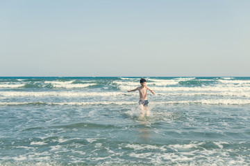 Boy Jumping In Sea Waves with Water Splashes. Concept of summer vacation