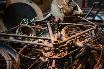 Fototapeta na wymiar Old rusty bikes, bicycles, retro car details and other vintage items lying in a heap and waiting for their museum restoration. Selective focus.
