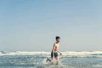 Fototapeta premium Boy Jumping In Sea Waves with Water Splashes. Concept of summer vacation