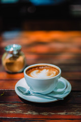 Hot coffee latte cappuccino spiral foam on wooden table in coffee shop cafe with vintage color tone filter background. With copy space for your text.