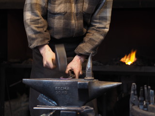 Blacksmith working metal with hammer in the forge for good luck on a christmas market in Cologne.