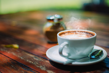Hot coffee latte cappuccino spiral foam on wooden table in coffee shop cafe with vintage color tone filter background. With copy space for your text. Color tone effect