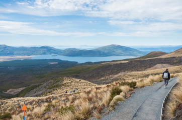 Young beautiful woman walking down volcanic path with lakes in the distance