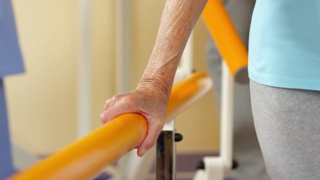 Mid-section shot of unrecognizable elderly woman holding on to handrails and learning to walk again at physiotherapy session