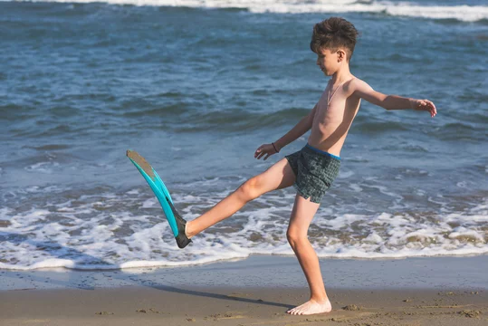 Happy teen boy in the swim flippers having fun on the sand оn the beach  during summer vacation Stock Photo | Adobe Stock