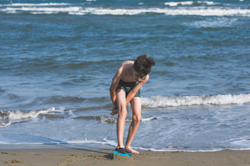 Fototapeta premium Happy teen boy in the swim flippers having fun on the sand оn the beach during summer vacation