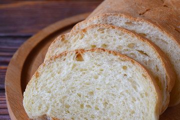 Fresh homemade bread sliced on wooden background.