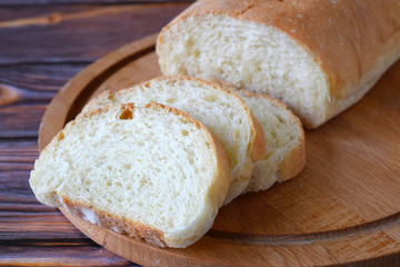 Fresh homemade bread sliced on wooden background.