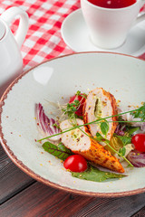 Fresh salad with chicken breast, arugula and tomato on a plate