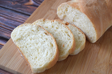 Fresh homemade bread sliced on wooden background.