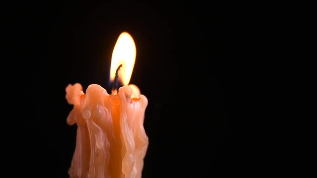 Candle flame closeup on dark background. Candle light border design. Melted wax candle burning at night, isolated on black background. Rotation. 4K UHD video footage. Slow motion 3840X2160