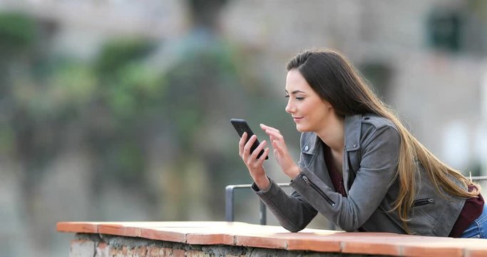Surprised woman finding smart phone content in a rural apartment balcony