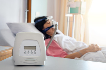 Obstructive sleep apnea therapy..Cpap machine is treating senior patient woman wearing Cpap mask sleeping smoothly without snoring in hospital room..