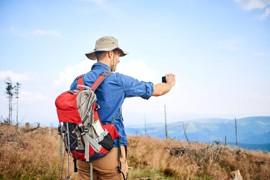 Man taking picture with his cell phone during hiking trip
