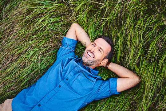 Relaxed happy man lying in grass