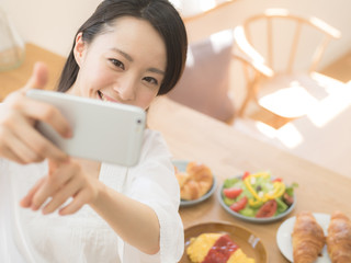 スマートフォンで料理の写真を撮る女性