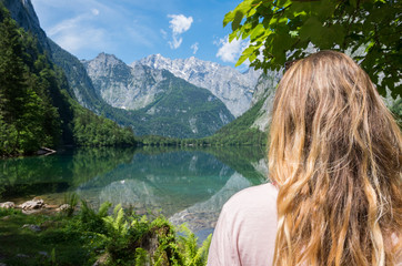 Young beautiful woman staring out over a still reflecting mountain lake