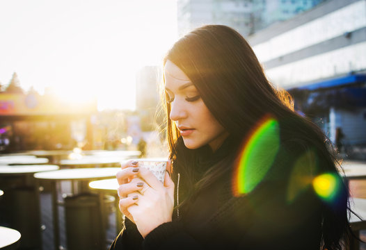 Portrait of young woman with cup of tea, outdoor in city center