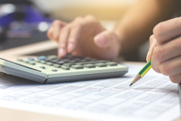 Close-up Businessman accountant hand holding pencil working on calculator to calculate financial data report. business financial concept.