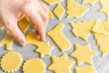 Woman preparing to bake homemade unbaked Christmas shortbread cookies in various shapes on tray. Appetizing golden color. Cozy home atmosphere holiday baking concept