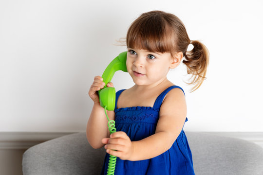 Toddler holding green corded phone against ear