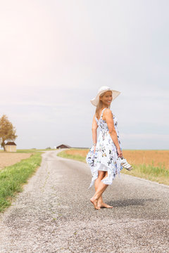 Mature woman walking on remote country lane in summer