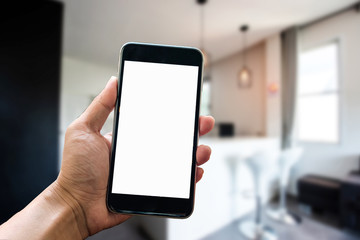A man hand holding smart phone device in the bright office room interior.
