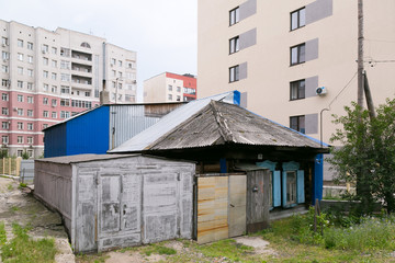 Old destroyed house among the new houses. Slums hut poor among new buildings and skyscrapers.