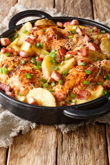 baked chicken fillet with potatoes, bacon and cheese close-up in a pan on the table. vertical