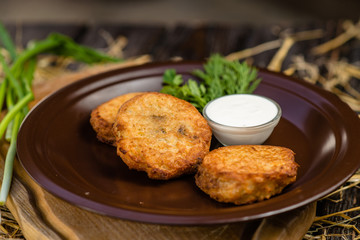 pancakes with sour cream and parsley on a clay plate