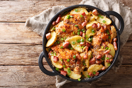 spicy chicken breast with potatoes, bacon and cheese close-up in a frying pan. Horizontal top view
